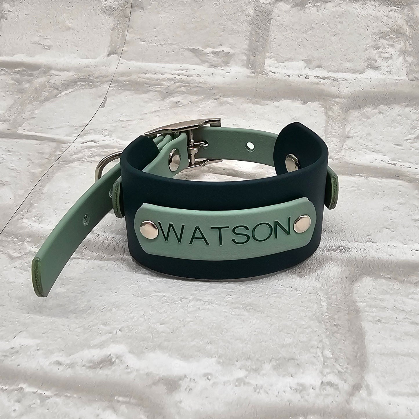 Green leather dog collar with 'Watson' engraving on a textured white background